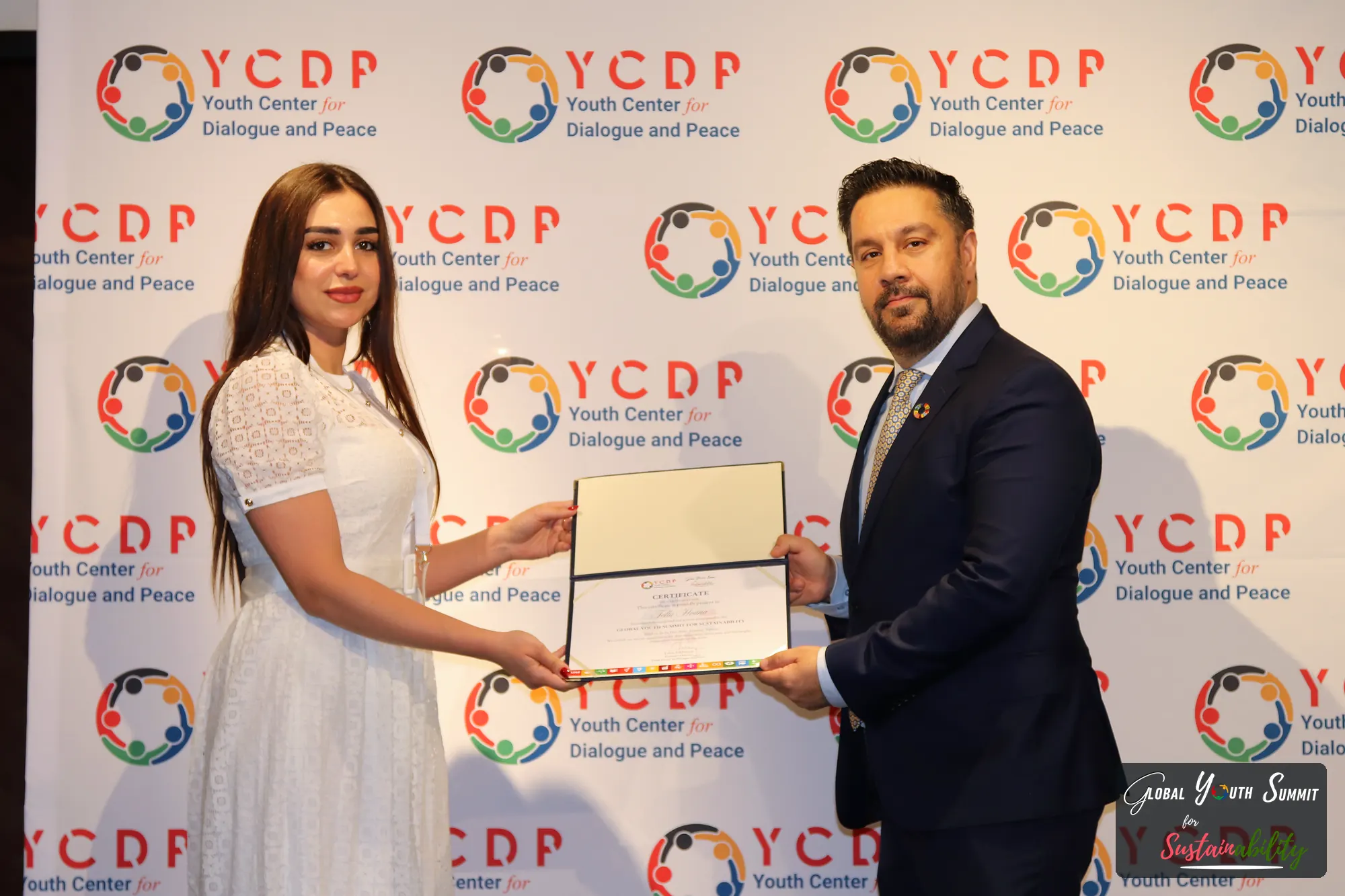 A delegate receiving a framed certificate at the YCDP backdrop